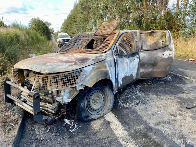 Carabineros y su director Ricardo Yáñez inspeccionan un vehículo policial quemado en el lugar donde fueron asesinados tres carabineros en la zona rural de Canete, región del Biobío