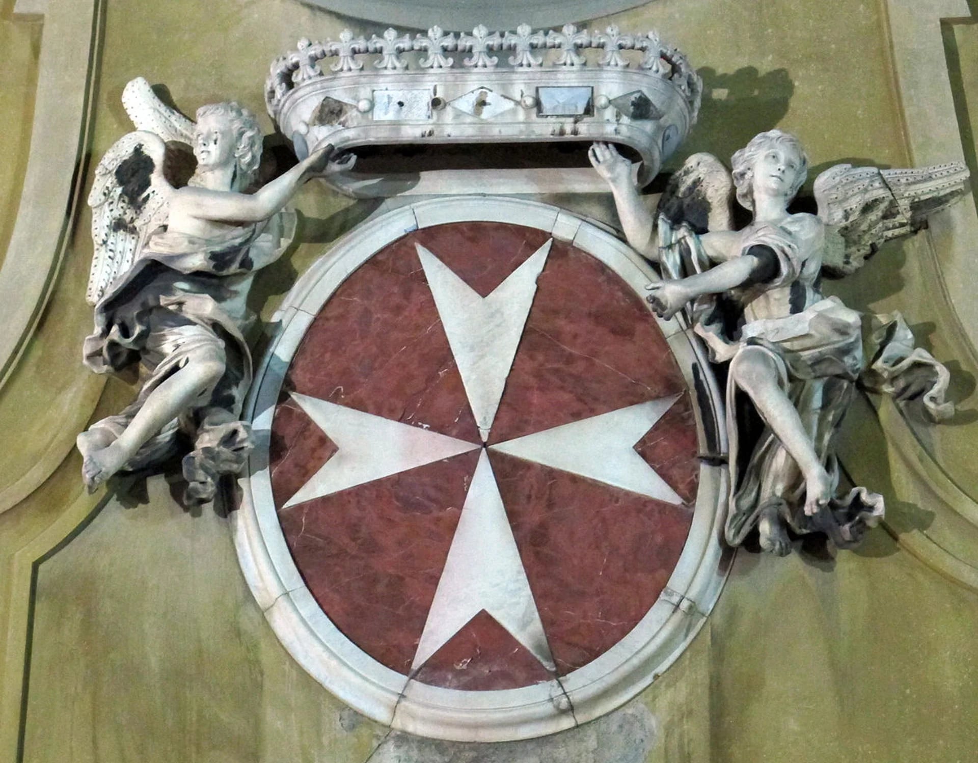 Escudo de la Orden de Malta, orden religiosa que por una disposición del Papa Pascual II hace actos de caridad y asistencia social de los peregrinos y del territorio cristiano a nivel mundial