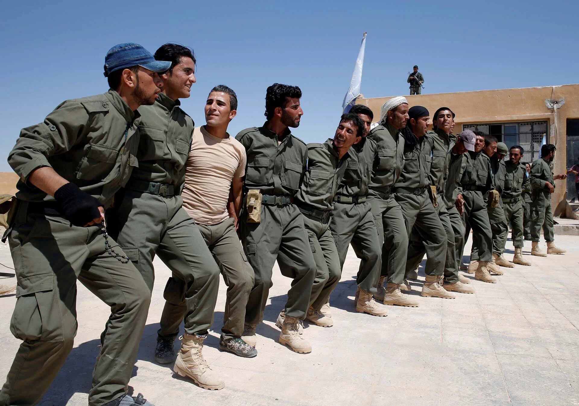 Los graduados de una fuerza de policía estadounidense, que esperan ser desplegados en Raqqa, bailan durante una ceremonia de egreso cerca del pueblo de Ain Issa, al norte de Raqqa, Siria