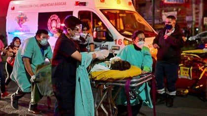 Emergency workers move an injured person on a stretcher at the site of a train accident after an elevated metro line collapsed in Mexico City on May 4, 2021. (Photo by PEDRO PARDO / AFP)