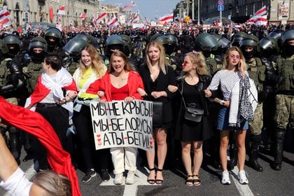 Mujeres con un cartel que dice "No somos ratas, somos bielorrusos, tú (Lukashenko) te vas!" (AP Photo)