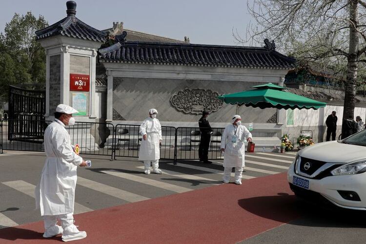 Trabajadores médicos en trajes protectores esperan para comprobar la temperatura del conductor de un coche frente a un cementerio, mientras China celebra un luto nacional por aquellos que murieron por el coronavirus, en la festividad de barrido de tumbas de Qingming, en Pekín, el 4 de abril de 2020. REUTERS/Thomas Peter
