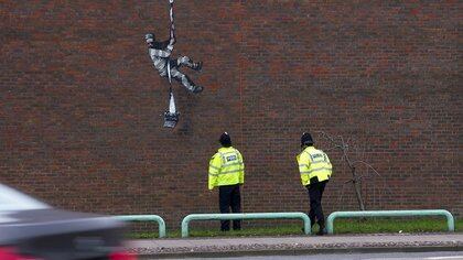 Agentes de policía miran el mural del artista Banksy en una pared de la prisión HM Reading en Reading, Reino Unido, en esta imagen obtenida de la cuenta oficial de Instagram del artista. @ banksy / banksy.co.uk a través de REUTERS 

