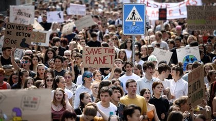 Una mujer sostiene una pancarta que dice 'Salva el planeta' mientras los manifestantes marchan durante una protesta contra el calentamiento global el 24 de mayo de 2019 en Lausana, Suiza. (AFP)