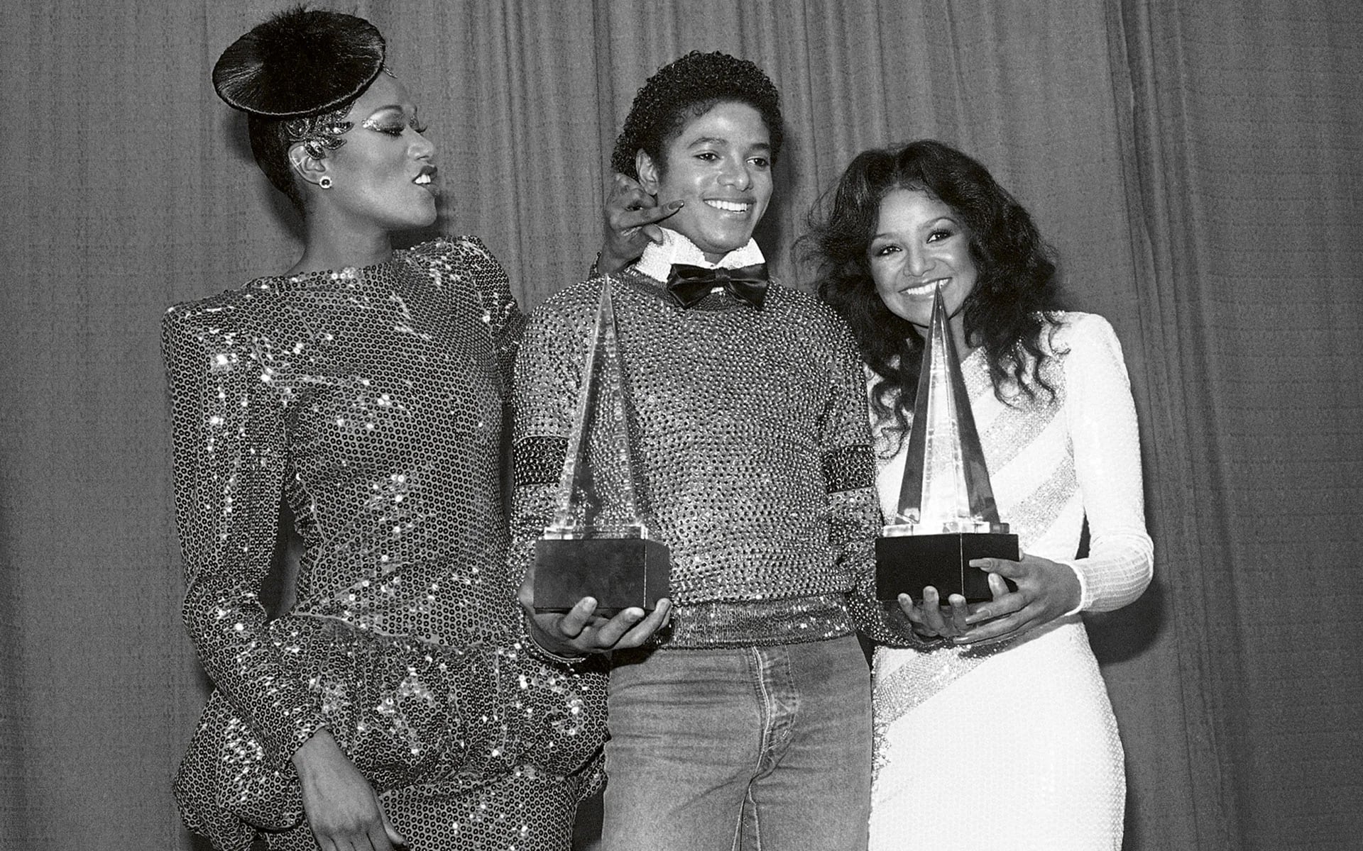 Bonnie Pointer acaricia la mejilla de Michael Jackson, al otro lado, Latoya, hermana del cantante en los American Music Awards en Los Angeles (Junio de 1981)