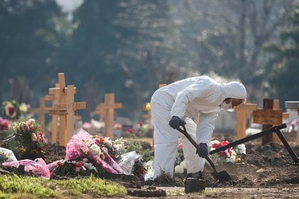 Un trabajador con equipo de protección cava tumbas en un cementerio de Buenos Aires (Reuters)