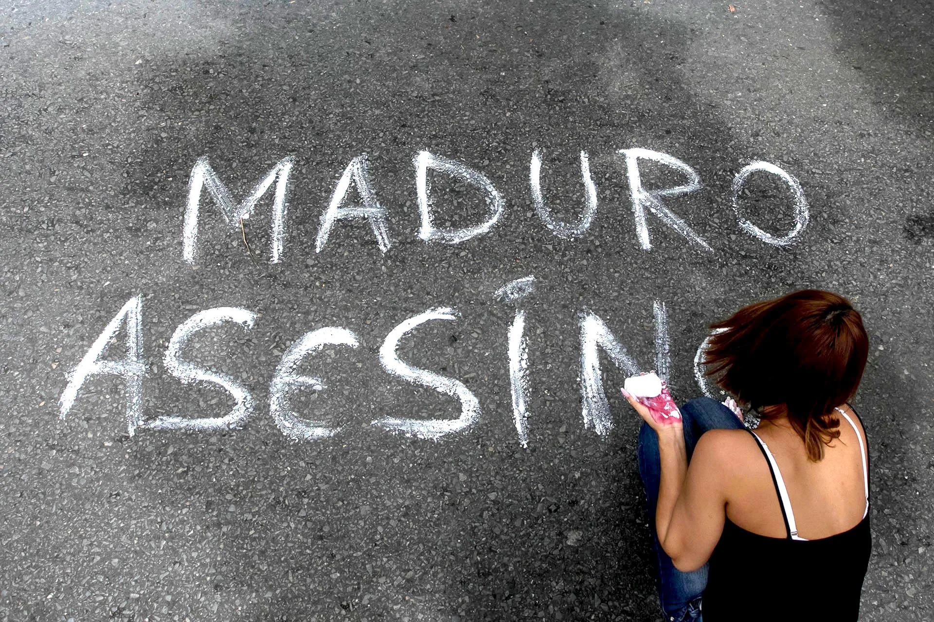 Una mujer escribe un mensaje sobre el asfalto durante una manifestación en Caracas