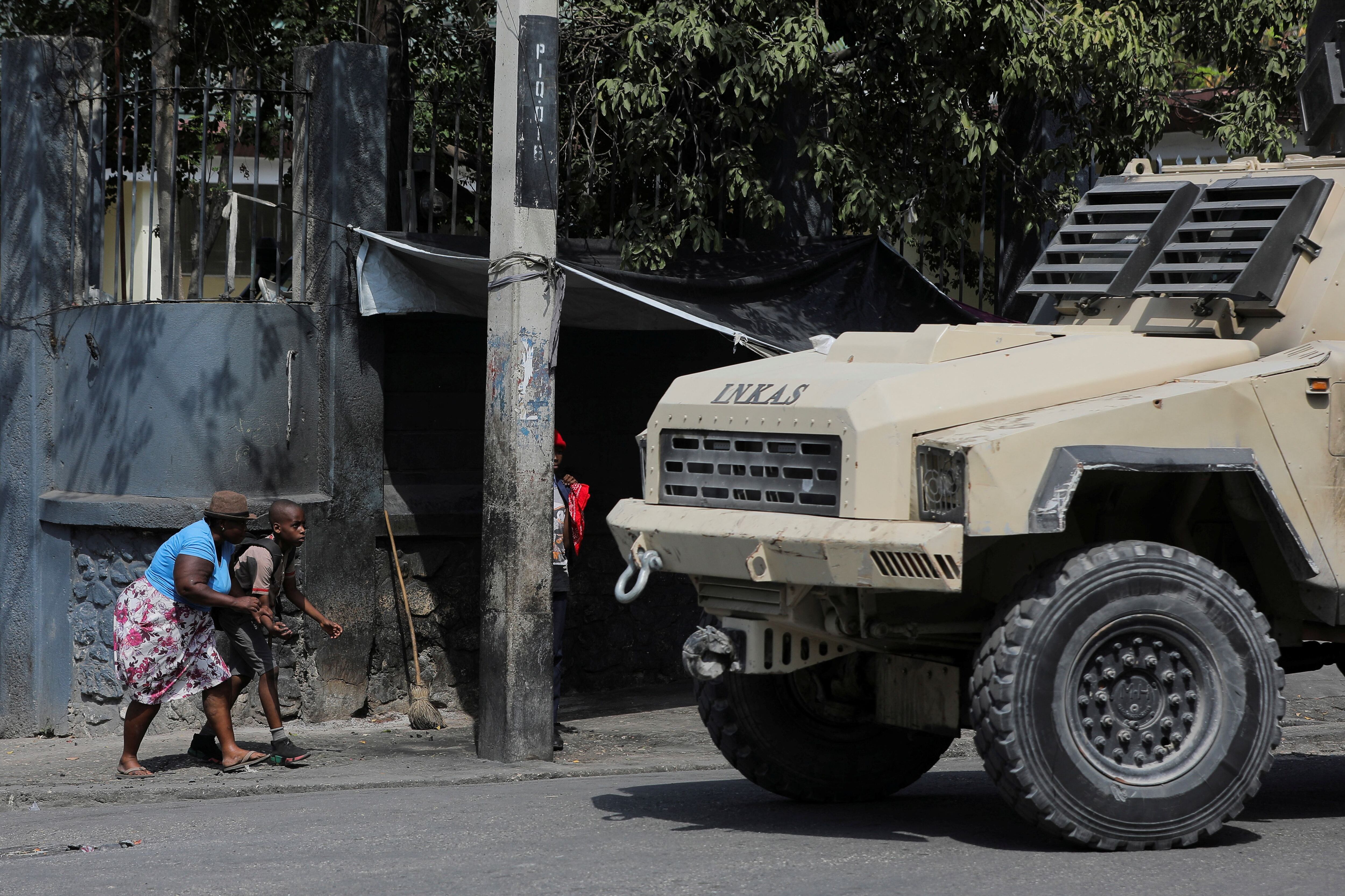 Una mujer y un niño se agachan cerca de un vehículo policial en Puerto Príncipe (REUTERS/Ralph Tedy Erol)