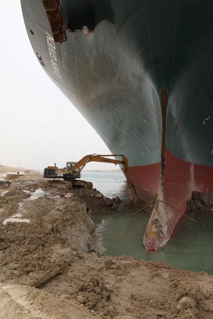 Una excavadora intenta liberar al buque portacontenedores Ever Given, uno de los portacontenedores más grandes del mundo, después de que encalló en el Canal de Suez. Suez Canal Authority/Handout via REUTERS