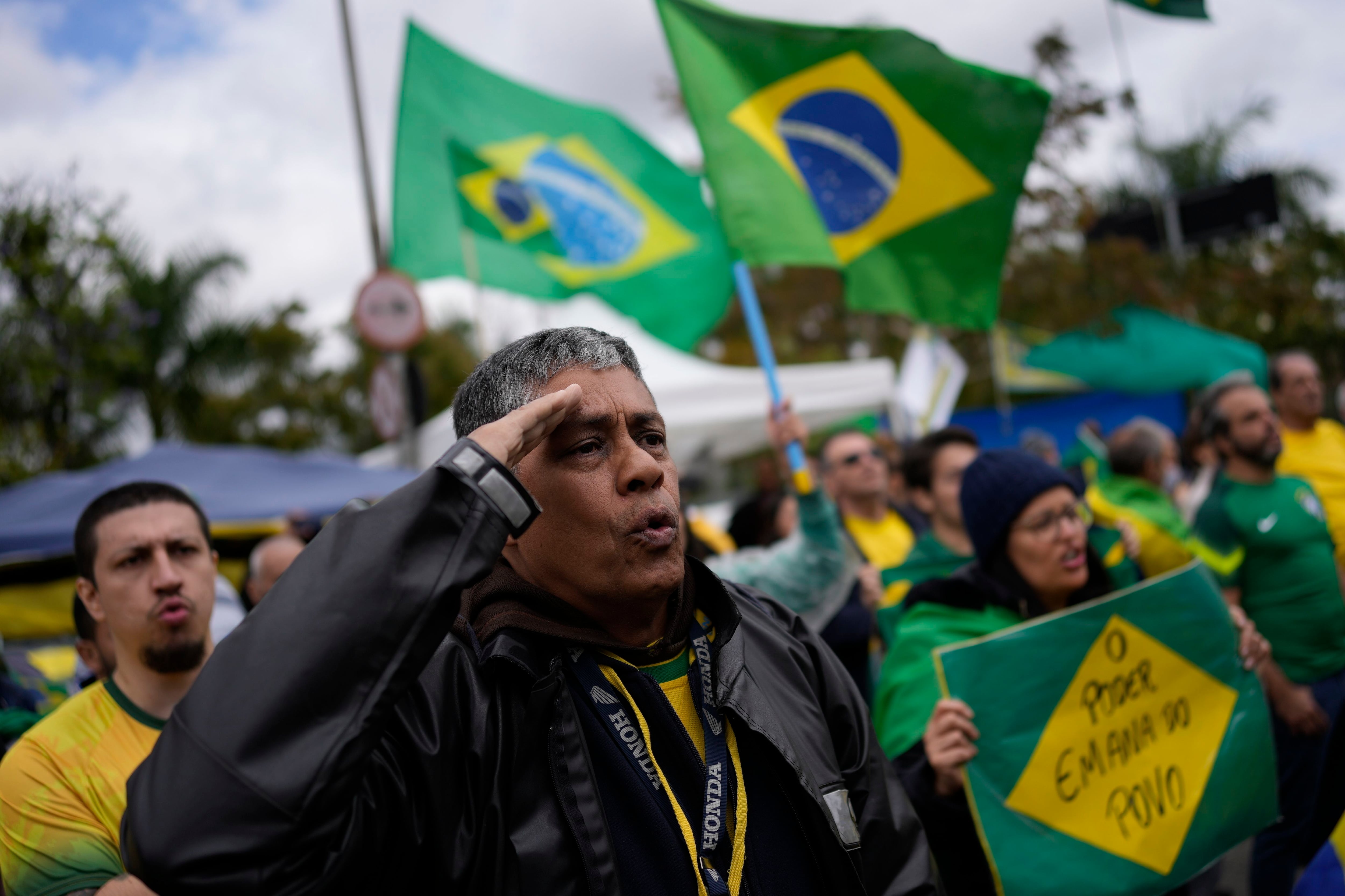 Un partidario del presidente brasileño Jair Bolsonaro saluda mientras canta el himno de la nación frente a una base militar (Foto AP/Matías Delacroix, Archivo)