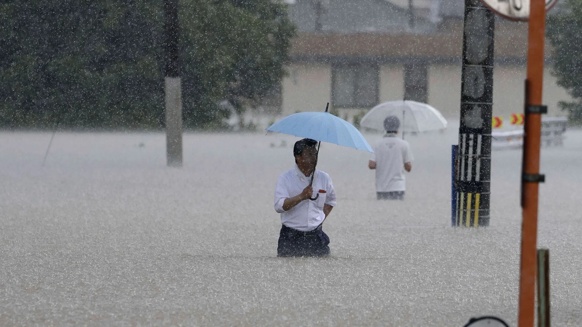 La gente camina por una calle debido a una fuerte lluvia en Kurume, prefectura de Fukuoka, sur de Japón, el lunes 10 de julio de 2023. Los científicos han advertido durante mucho tiempo que se esperan lluvias más extremas en un mundo que se calienta. (Noticias de Kyodo vía AP)