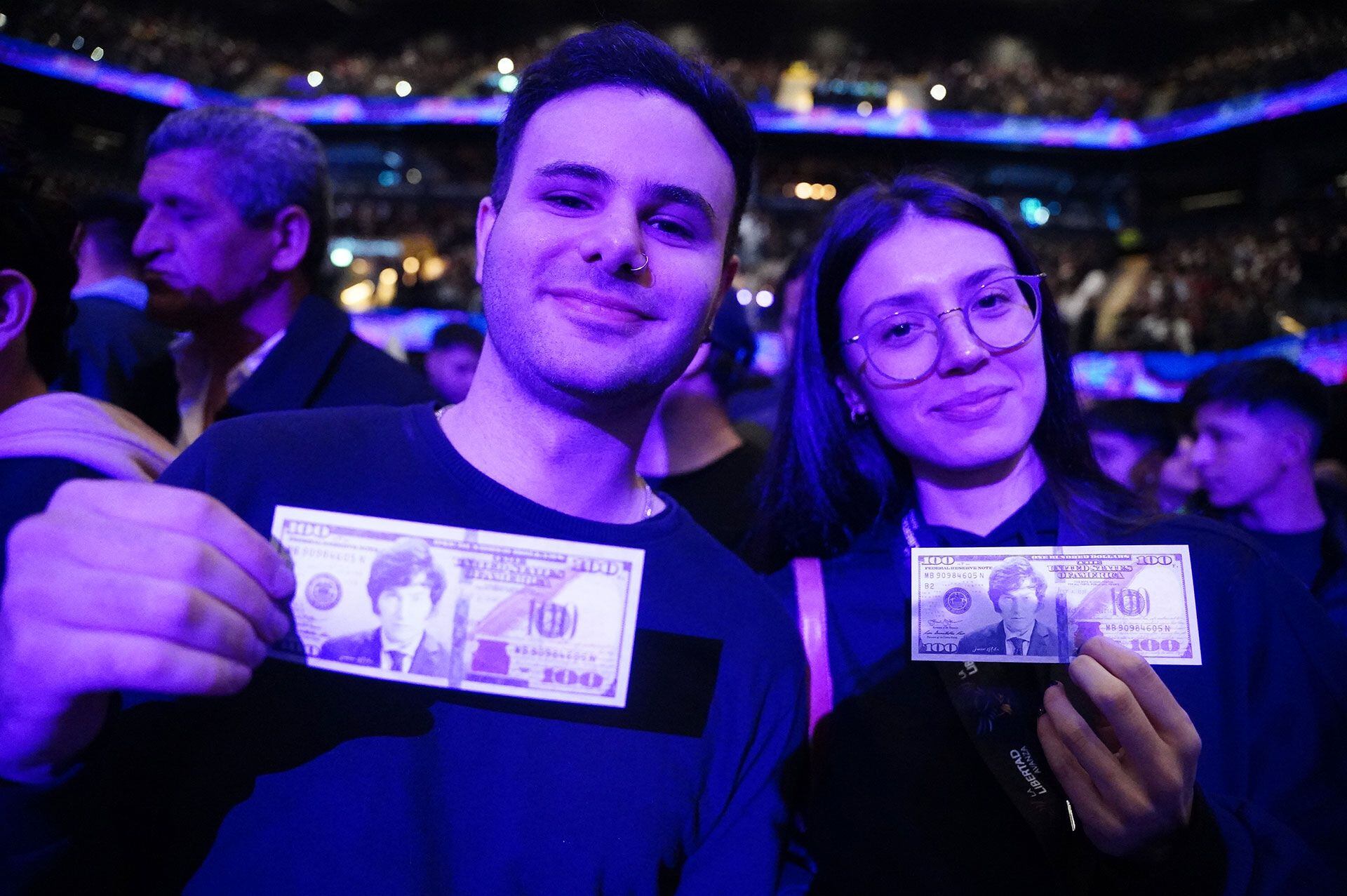 Dos simpatizantes de Milei sosteniendo dólares con el rostro del candidato presidencial 