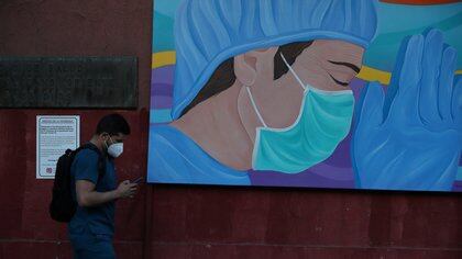 A health worker walks past a painting placed as a sign of gratitude by neighbors to health workers at a hospitals area, during the coronavirus disease (COVID-19) outbreak in Santiago, Chile March 9, 2021. REUTERS/Ivan Alvarado