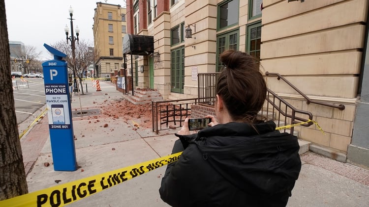 Una mujer toma una foto de ladrillos y escombros que cayeron de un edificio en el centro de Salt Lake City después de un terremoto el 18 de marzo de 2020 en Utah (George Frey/Getty Images/AFP)