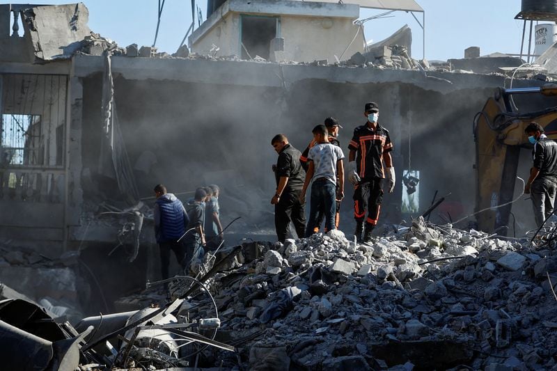 Palestinos buscan víctimas bajo los escombros tras los ataques israelíes en medio del actual conflicto con el grupo islamista palestino Hamas, en Jan Yunis, en el sur de la Franja de Gaza. 13 de octubre de 2023 (Reuters-Ibraheem Abu Mustafa)