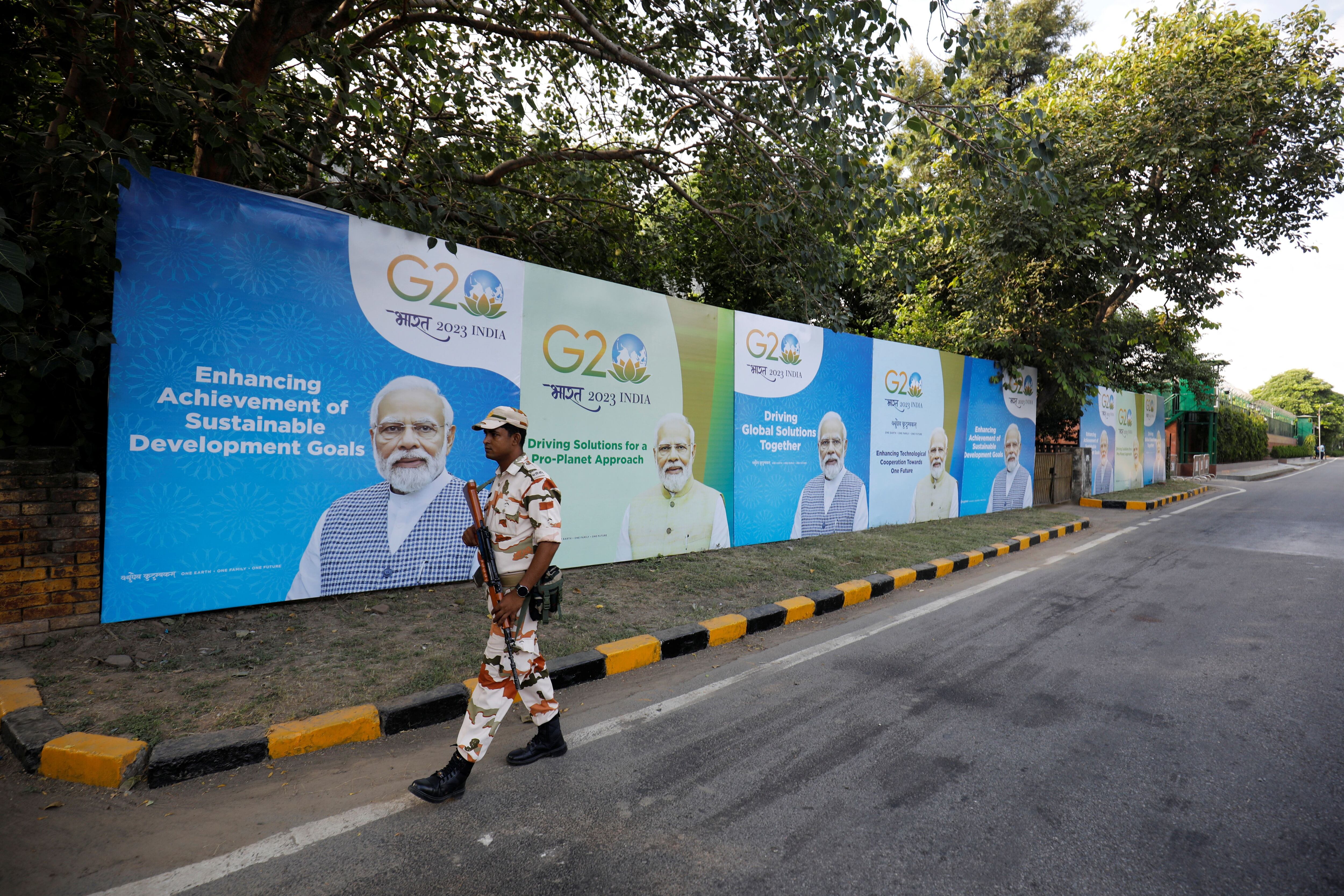 Un miembro de las fuerzas de seguridad patrulla junto a unas vallas en las que aparece el primer ministro indio, Narendra Modi, en una carretera vacía antes de la Cumbre del G20 en Nueva Delhi, India, 8 de septiembre de 2023. REUTERS/Amit Dave