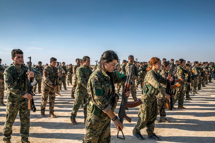 FILE -- Kurdish fighters with the American-backed Syrian Democratic Forces in Hukumya, Syria, stand in formation during a funeral for comrades killed in fighting against the Islamic State group on Oct. 11, 2017. In a major shift in U.S. military policy in Syria, the White House said on Sunday, Oct. 6, 2019, that President Donald Trump had given his endorsement for a Turkish military operation that would sweep away American-backed Kurdish forces near the border in Syria. (Ivor Prickett/The New York Times)