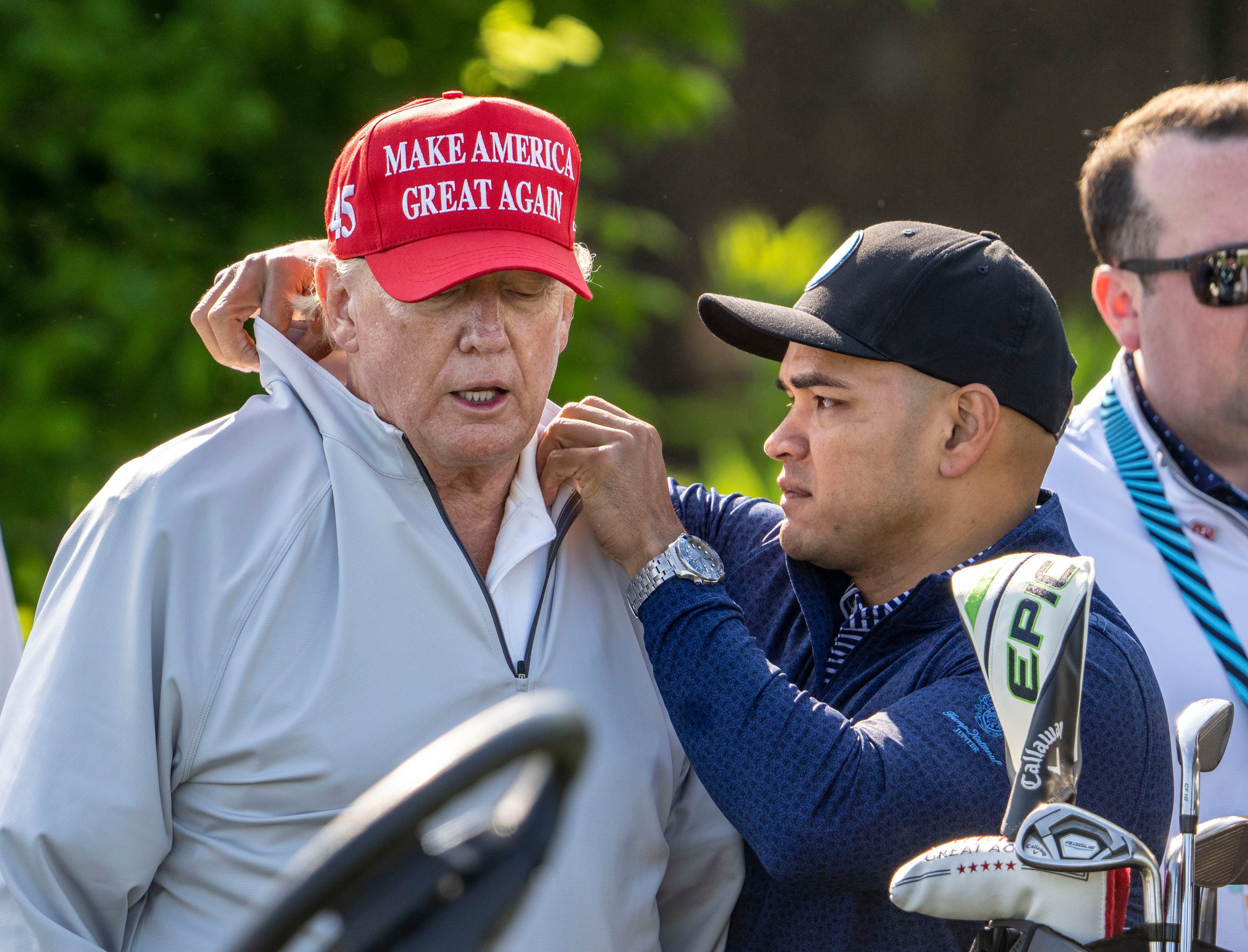 ARCHIVO - Walt Nauta, ayudante personal de Donald Trump, le ayuda con una camisa durante el torneo pro-am de LIV Golf en el Trump National Golf Club (Doug Mills/The New York Times)