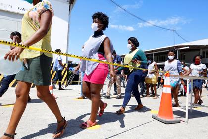 Trabajadores caminan a una distancia segura entre ellos durante un descanso en una fabrica local de ropa que produce máscaras protectoras en Puerto Príncipe, Haití, el 21 de abril de 2020. (REUTERS/Jeanty Junior Augustin)