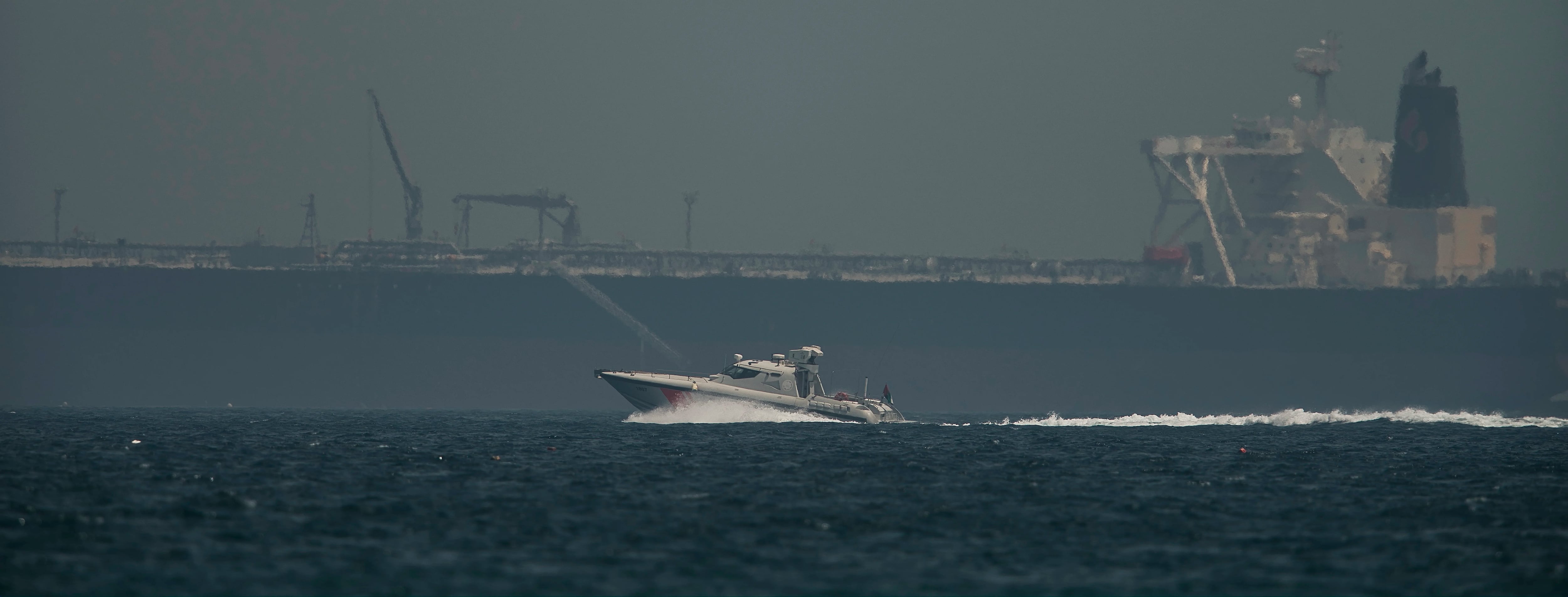 Un navío de la Guardia Costera emiratí pasa junto a un petrolero frente a la costa de Fujairah, Emiratos Árabes Unidos, el lunes 13 de mayo de 2019. (AP Foto/Jon Gambrell)