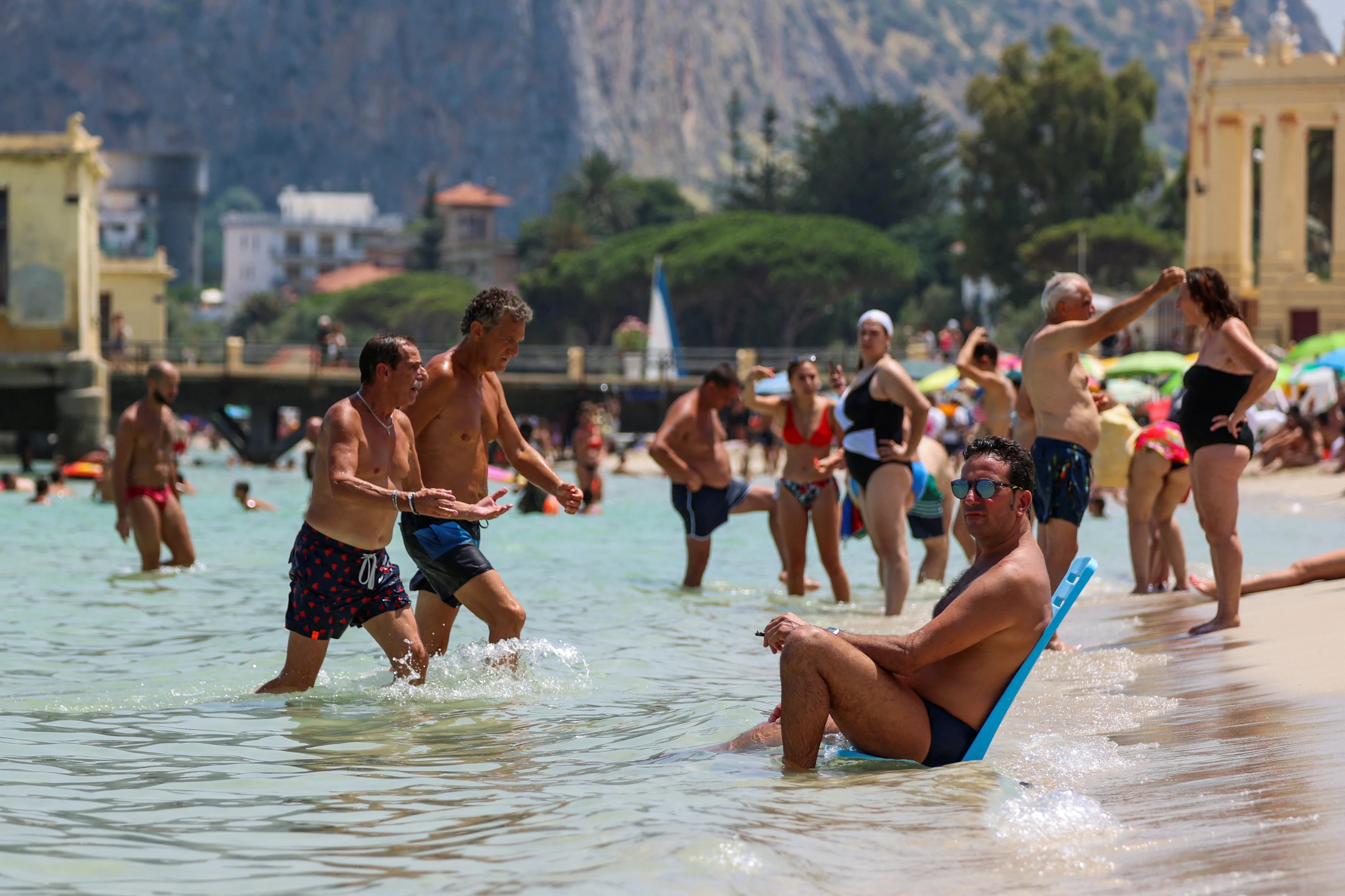 Un hombre sentado en el mar en la playa de Mondello, en Palermo, Sicilia. (REUTERS/Igor Petyx)