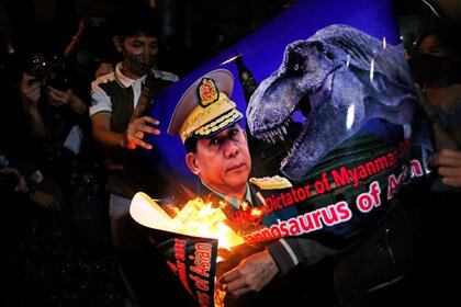Un grupo de birmanos queman un cartel con la cara del general golpista Min Aung Hlaing a quien comparan con un dinosaurio. REUTERS/Jorge Silva