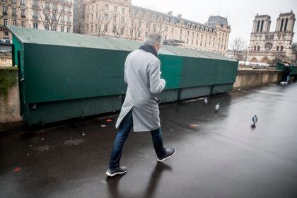 Un hombre pasea por uno de los muelles del Sena ante una caseta de libros de ocasión cerrada por la pandemia de covid.EFE/MOHAMMED BADRA

