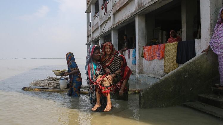 Dos mujeres lidian con la inundación en el norte de Bangladesh (Photo by REHMAN ASAD / AFP)