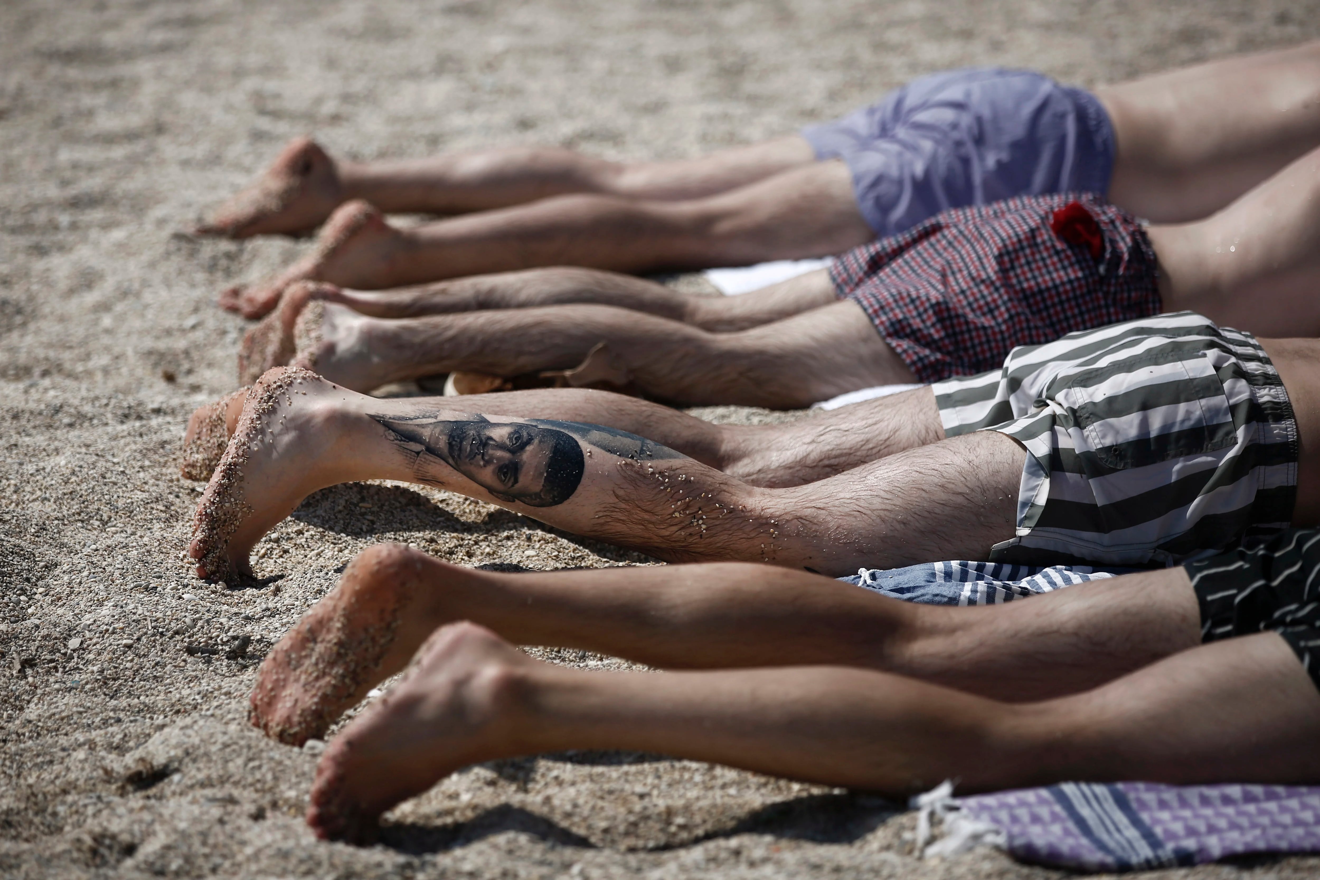 Un grupo de hombres toma sol en una playa de Atenas, Grecia
