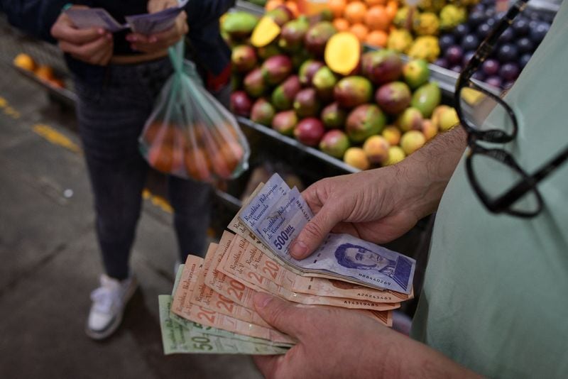FOTO DE ARCHIVO- Un cliente cuenta billetes de bolívares venezolanos en un puesto de un mercado municipal en Caracas, Venezuela, 10 de febrero de 2023. REUTERS/Gaby Oraa