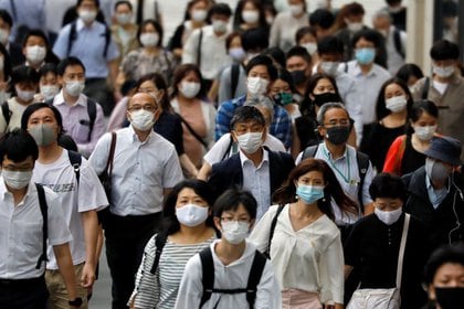 Varios peatones con mascarillas caminan cerca de una estación durante el brote de la enfermedad del nuevo coronavirus (COVID-19) en Tokio, Japón, el 30 de julio de 2020. REUTERS/Issei Kato