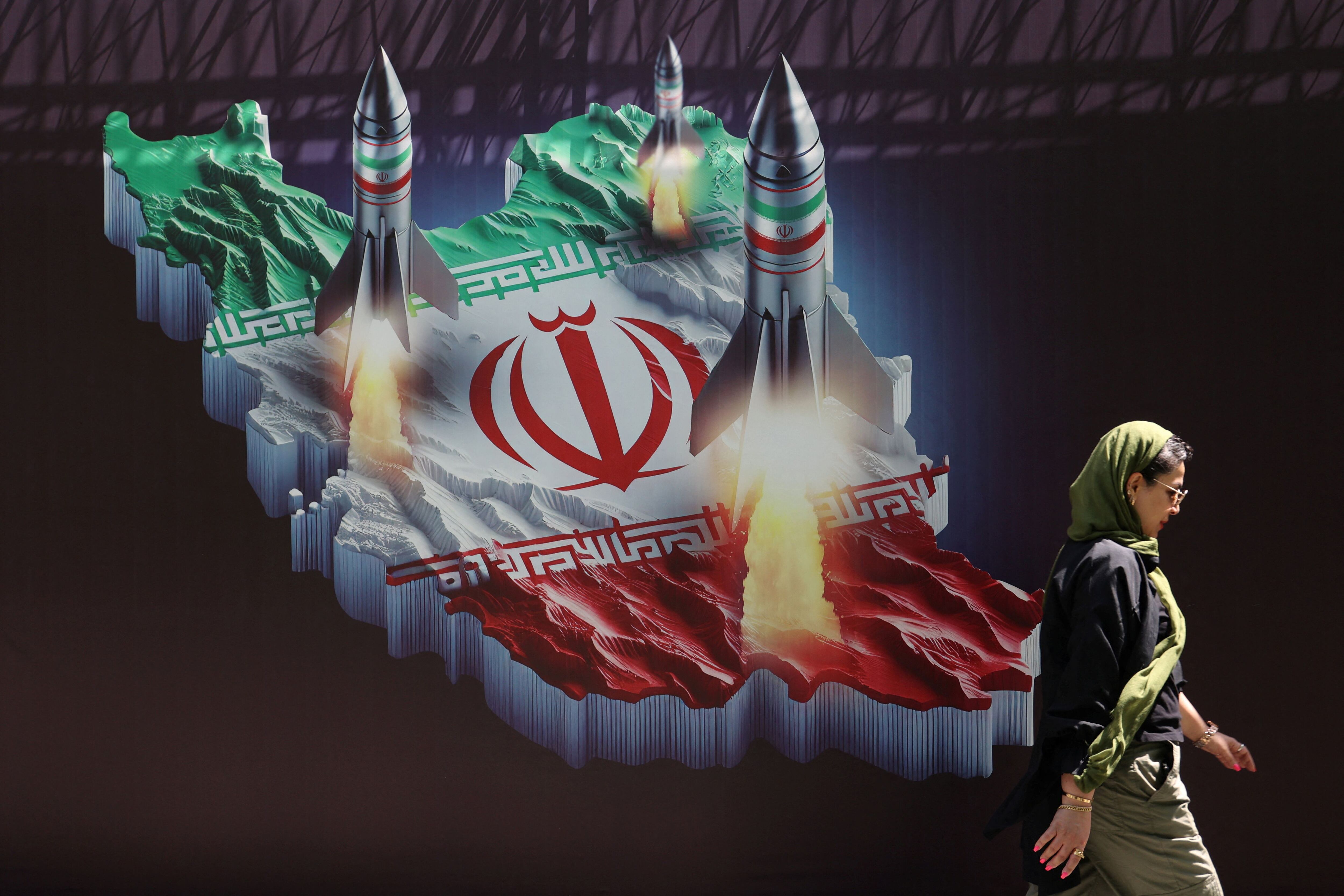 Una mujer iraní pasa junto a una pancarta antiisraelí con una imagen de misiles iraníes en una calle de Teherán, Irán, el 19 de abril de 2024. Majid Asgaripour/WANA (Agencia de Noticias de Asia Occidental) vía REUTERS