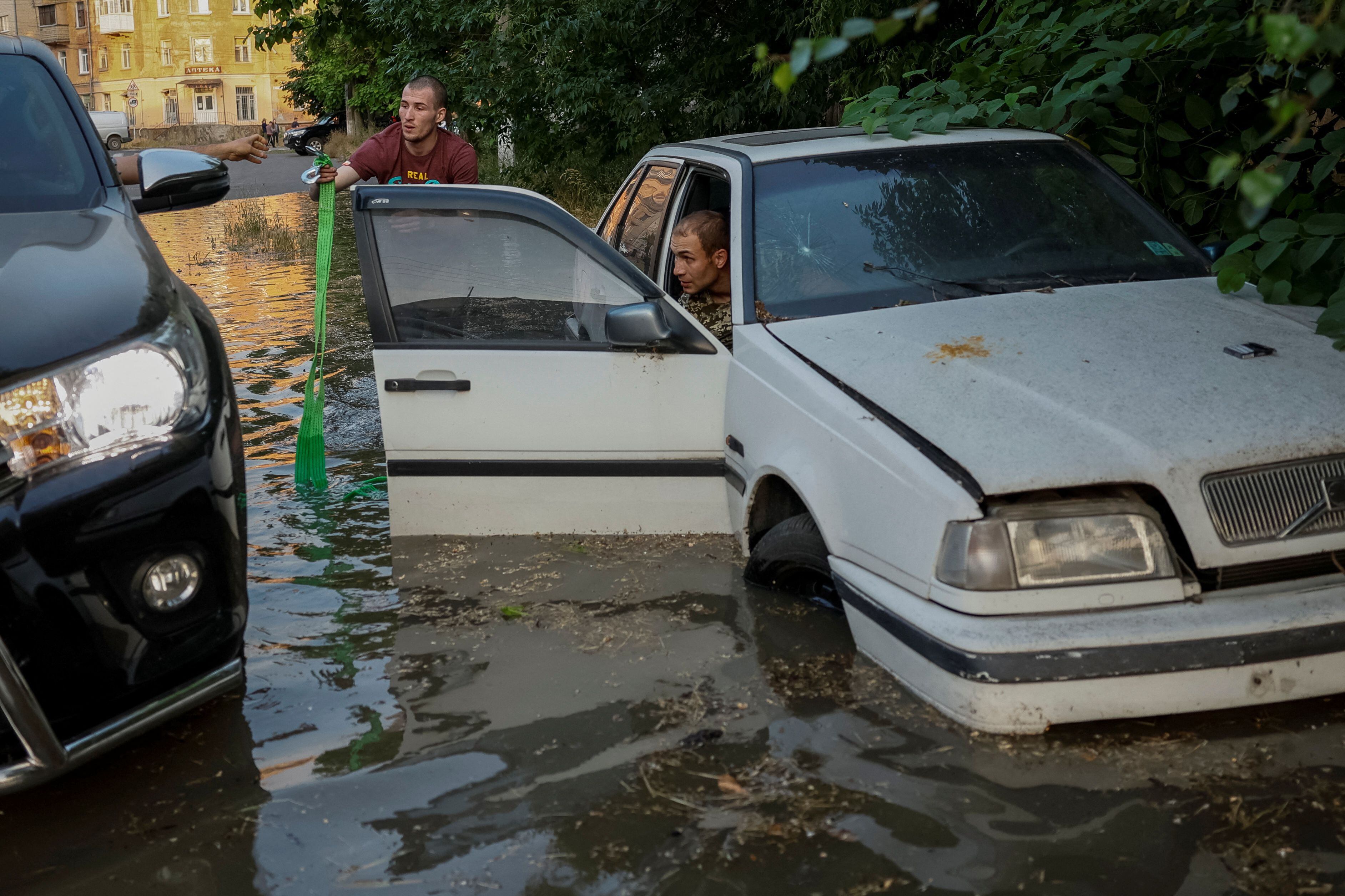 Unos residentes tratan de sacar un auto de la inundación con una camioneta.