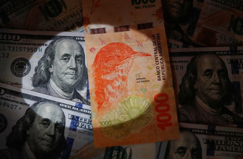 Foto de archivo - Un billete de 1.000 pesos argentinos sobre varios billetes de dólar estadounidense a modo ilustrativo. REUTERS/Agustin Marcarian/