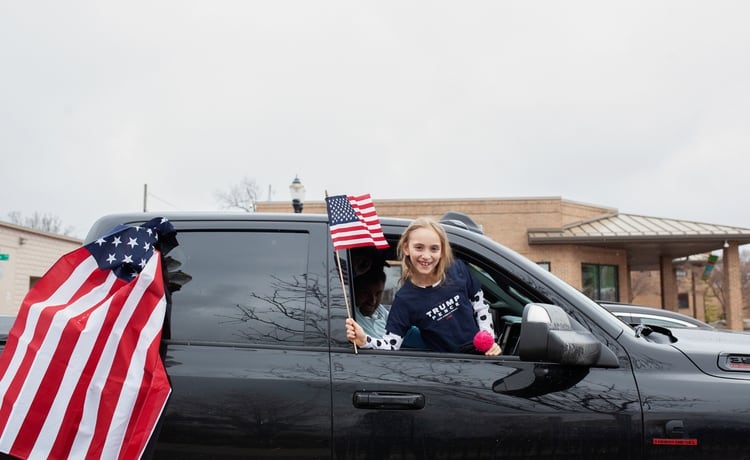 Una joven flamea una bandera estadounidense desde un automóvil durante la protesta contra la gobernadora de Michigan (Reuters/ Seth Herald)