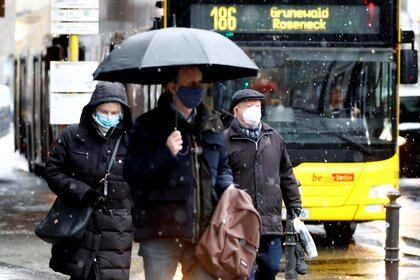 People wear face masks as they walk past a bus during lockdown due to the coronavirus disease (COVID-19) pandemic in Berlin, Germany, January 19, 2021.    REUTERS/Fabrizio Bensch