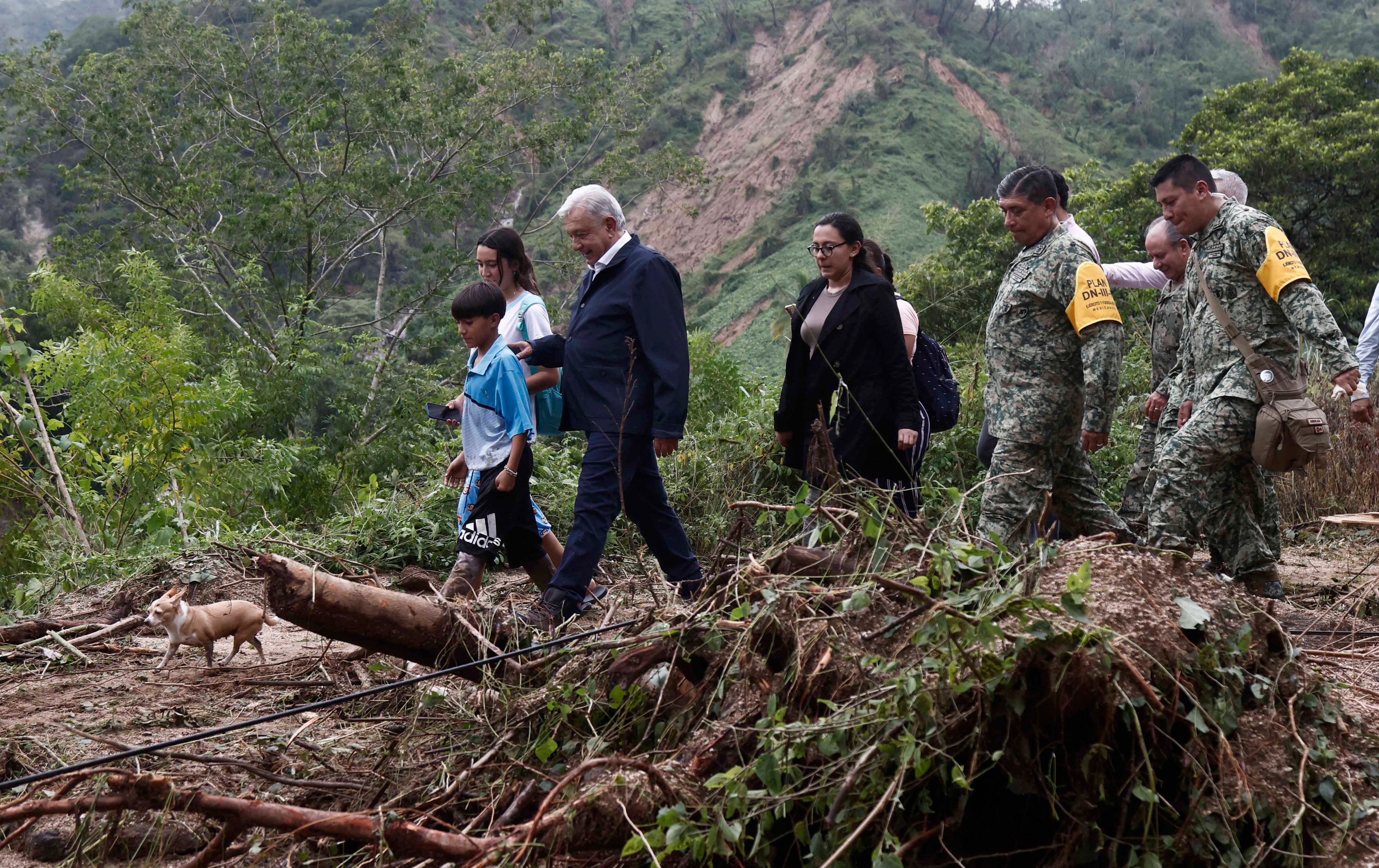Mexican President Andres Manuel Lopez Obrador (C) and members of his cabinet visit the Kilometro 42 community, near Acapulco, Guerrero State, Mexico, after the passage of Hurricane Otis, on October 25, 2023. Mexican authorities rushed to send emergency aid, restore communications and assess damage in the Pacific beach resort of Acapulco on Wednesday after a powerful hurricane left a trail of destruction and tourists stranded. (Photo by Rodrigo OROPEZA / AFP)