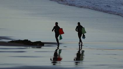 Dos surfistas en la playa vizcaína de Sopelana se dirigen a realizar surf (EFE/LUIS TEJIDO)