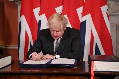 Britain's Prime Minister Boris Johnson signs the Brexit trade deal with the EU at number 10 Downing Street in London, Britain December 30, 2020. Leon Neal/Pool via REUTERS
