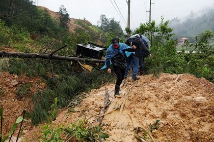 Hombres cruzan un deslizamiento de tierra que bloquea una carretera tras el paso de Tempest Eta en Purulha, Guatemala (Reuters)