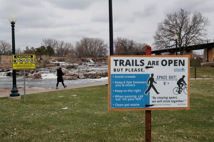 Una mujer camina detrás de una señal que pide distanciamiento social en Dakota del Sur (REUTERS/Shannon Stapleton/File Photo)