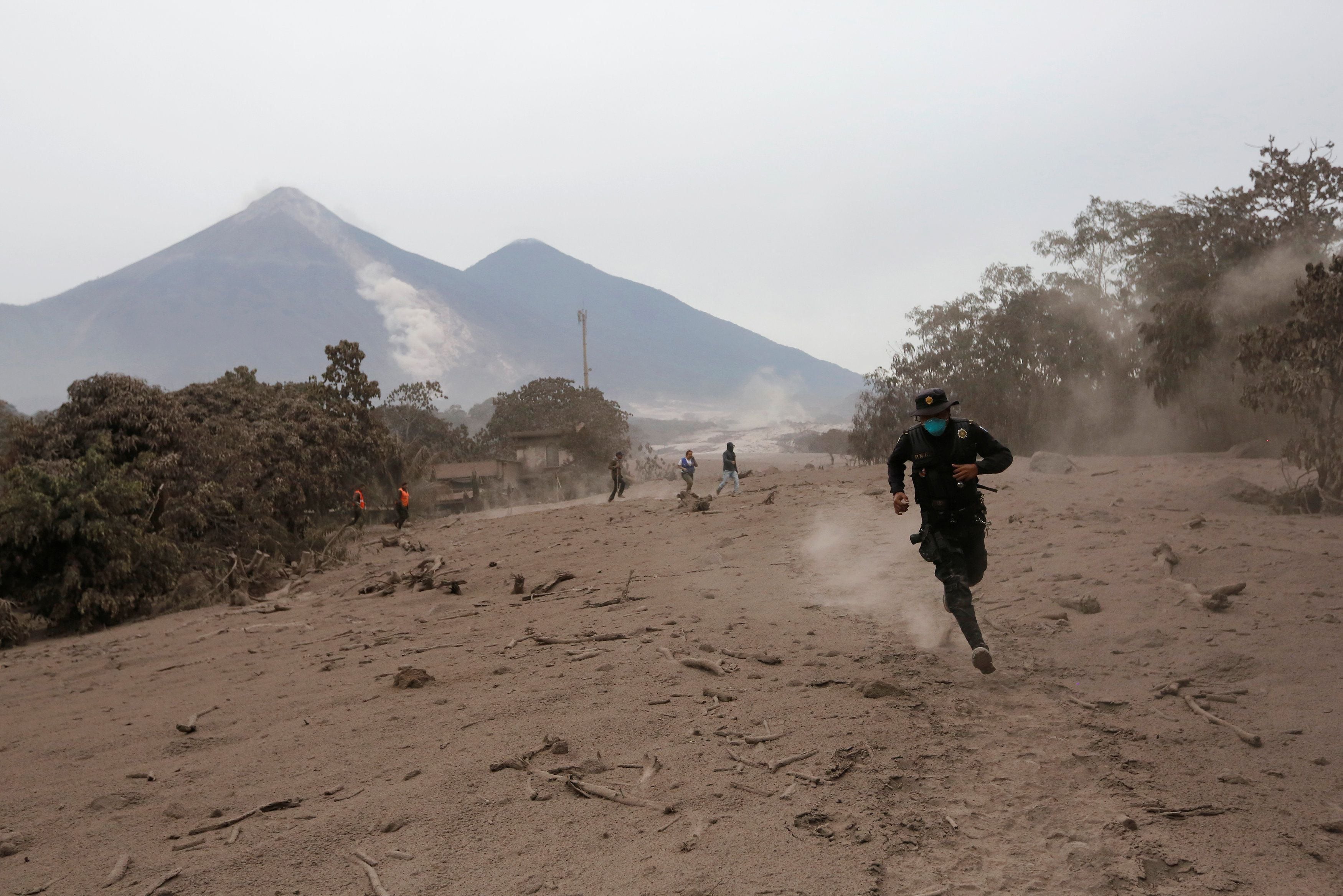 Un oficial de policía huye después de que el volcán Fuego arrojara un nuevo flujo piroclástico en la comunidad de San Miguel Los Lotes en Escuintla, Guatemala, el 4 de junio de 2018.(Reuters/Luis Echeverría)