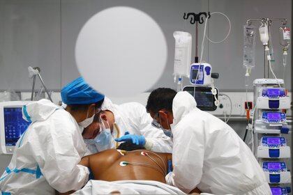 Un miembro del personal médico atiende a un paciente con COVID-19 dentro de la sala de la UCI del nuevo hospital pandémico Enfermera Isabel Zendal en medio del brote de la enfermedad por coronavirus (COVID-19) en Madrid, España, el 29 de enero de 2021. Imagen tomada a través de un cristal. REUTERS