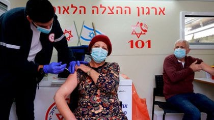 A paramedic administers a dose of the Pfizer/BioNTech coronavirus vaccine to a woman inside a mobile clinic of Magen David Adom at the Mahane Yehuda Market in Jerusalem on February 22, 2021. - Israel's inoculation campaign is regarded as the world's fastest, with one dose of the Pfizer/BioNTech vaccine administered to 4.25 million people out of its nine million-strong population since December, according to the latest health ministry figures. (Photo by MENAHEM KAHANA / AFP)