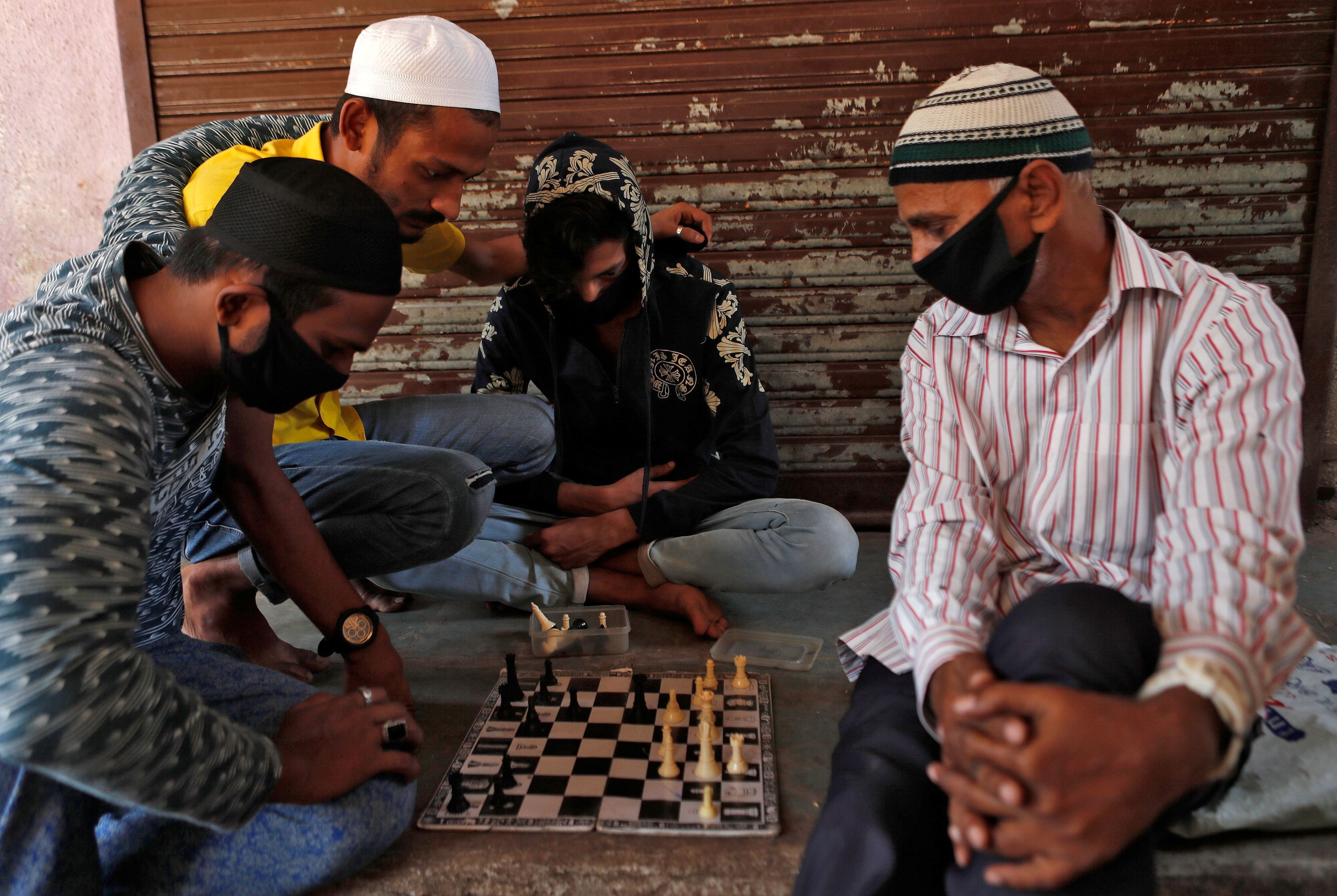 Un grupo de hombres juegan al ajedrez en la puerta de un local cerrado en Dharavi, un barrio carenciado en Mumbai, India, durante la pandemia de COVID-19. (REUTERS/Francis Mascarenhas) 