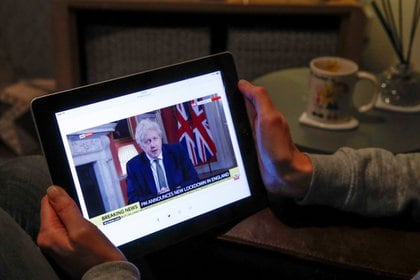 Una maestra británica mira el mensaje de Boris Johnson en una tableta. Foto: REUTERS/Andrew Couldridge
