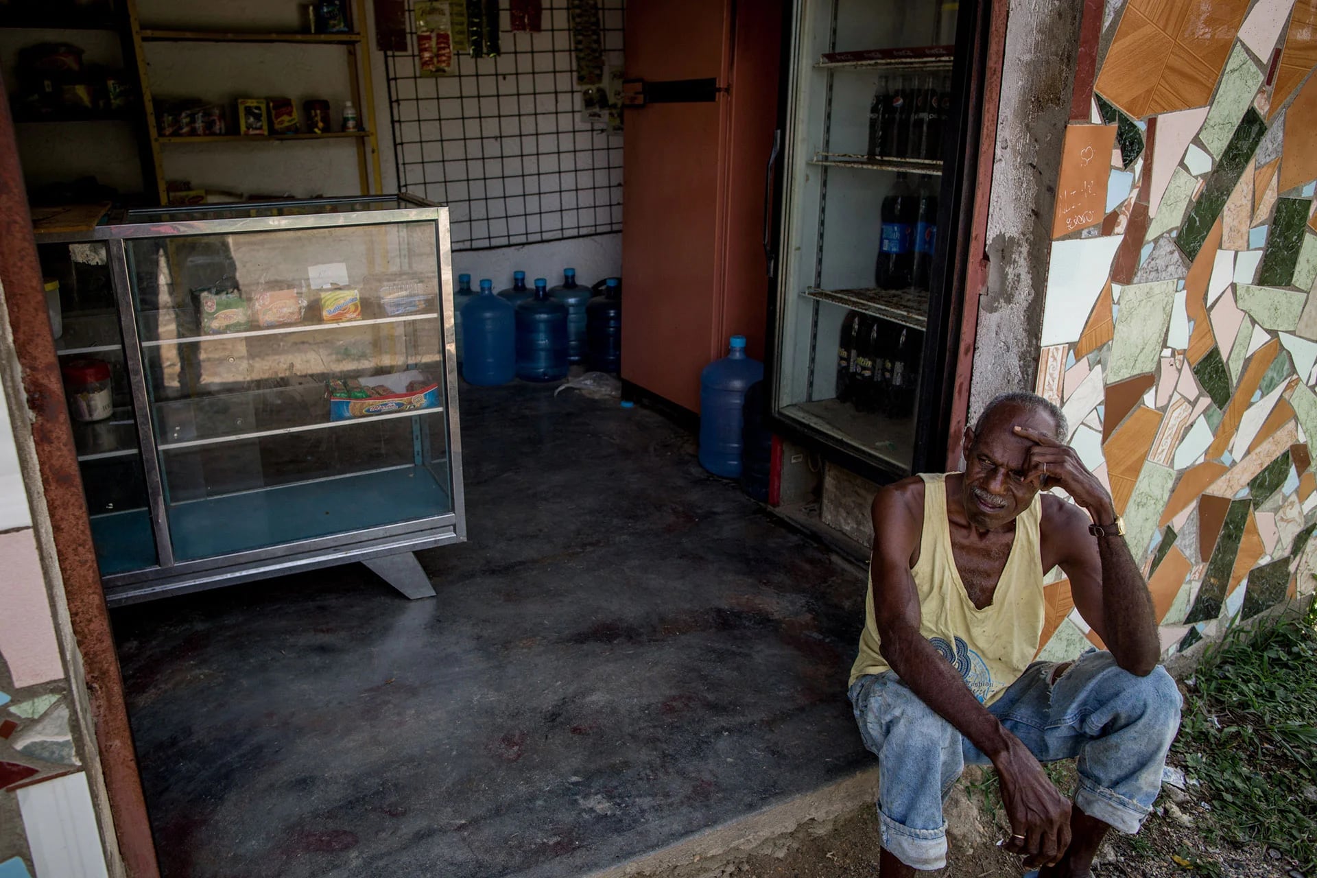 Un hombre descansa en la entrada de su tienda en Barlovento. Desde enero que no le reparten comida. Apenas subsiste (Washington Post)