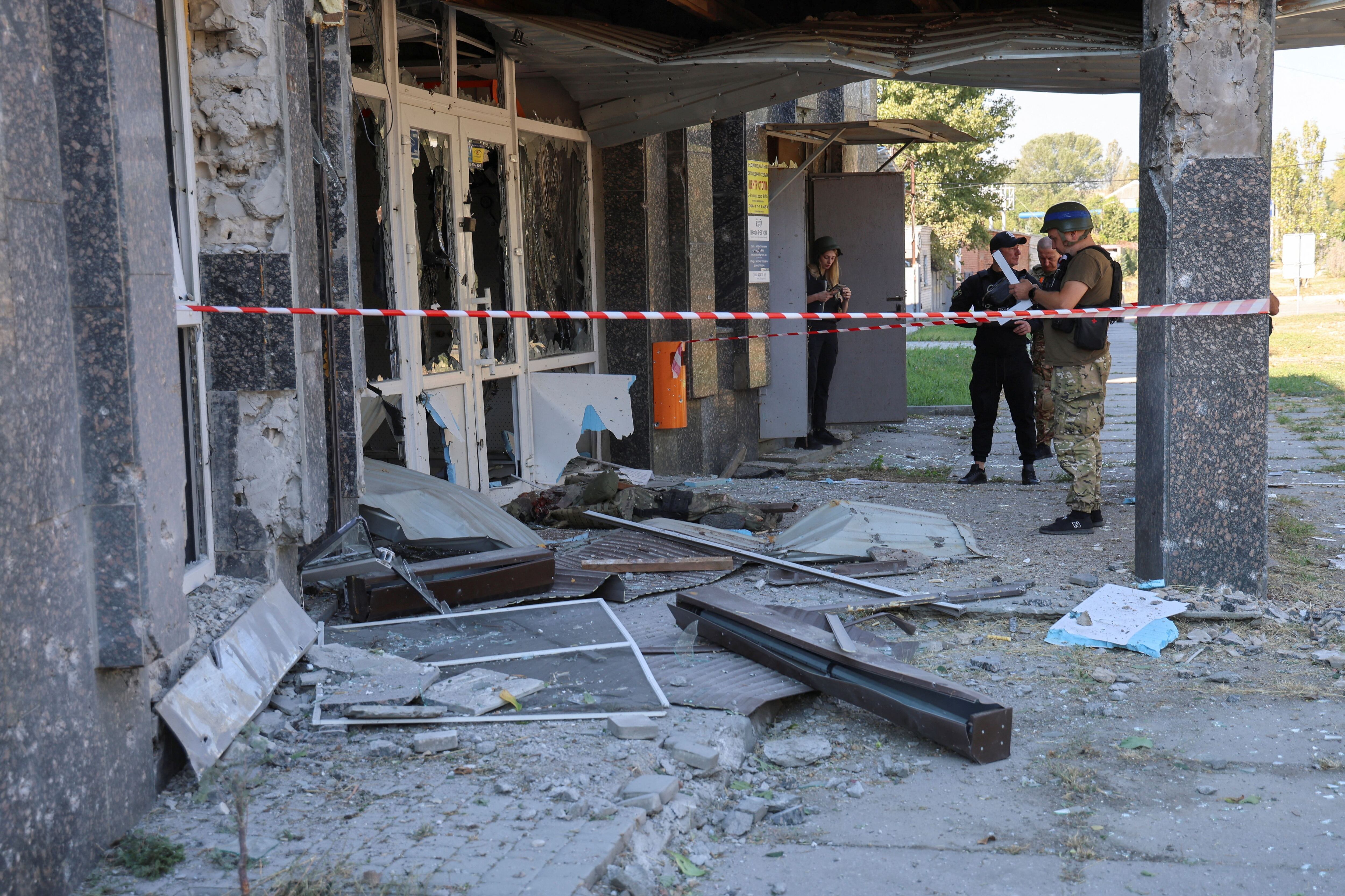 Agentes de policía junto al cuerpo de un compañero muerto durante un ataque militar ruso en Kherson  (REUTERS/Ivan Antypenko)