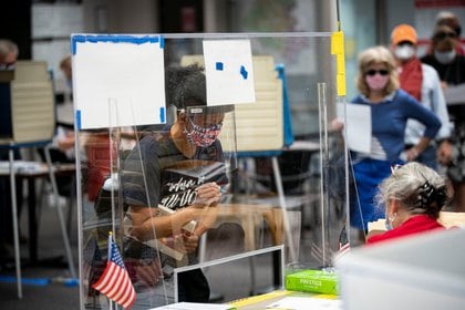 Una mujer usa una máscara y un protector facial cuando se registra para recibir su boleta en un lugar de votación anticipada en el Centro de Gobierno del Condado de Fairfax el 18 de septiembre de 2020. REUTERS / Al Drago