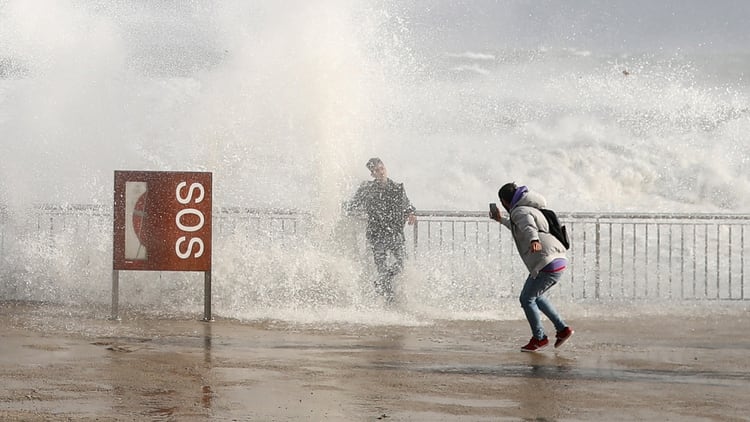 Turistas toman fotografías de las olas durante la tormenta 